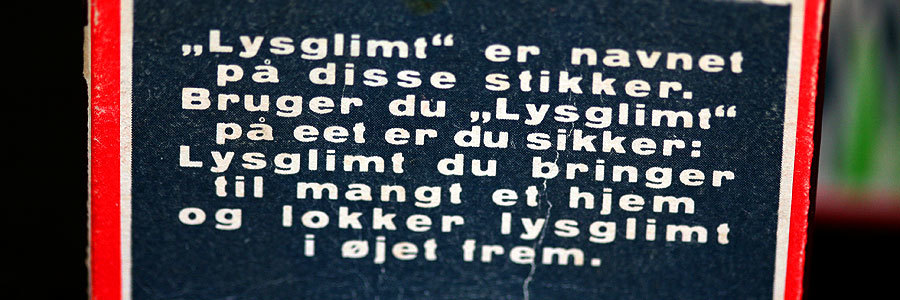 Foto af bagsiden på en LYSGLIMT tændstiksæske. Teksten lyder: "Lysglimt er navnet på disse stikker. Bruger du Lysglimt på eet er du sikker: Lysglimt du bringer til mangt et hjem og lokker lysglimt i øjet frem.